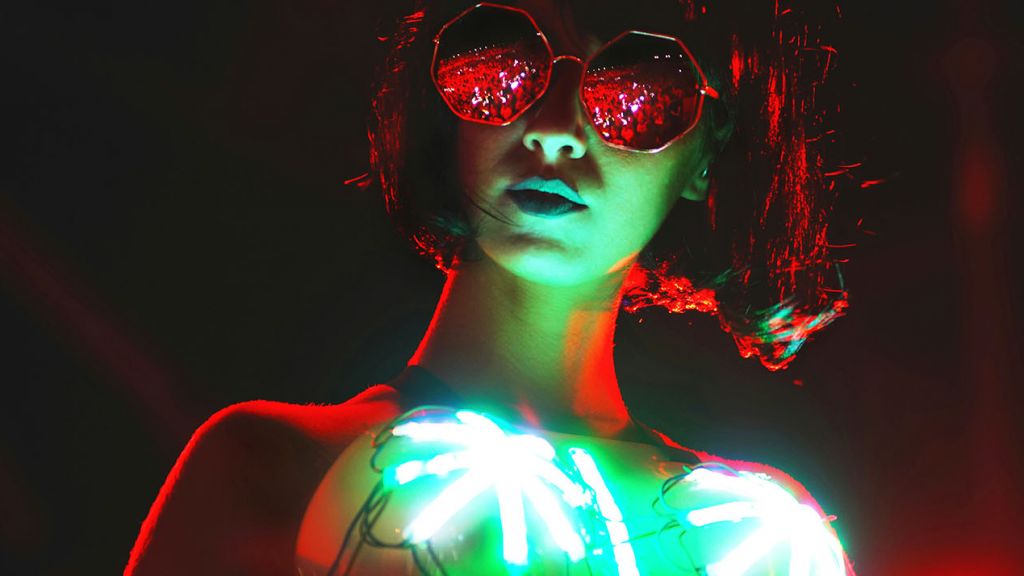 Une femme dans la nuit avec lunettes noires et des leds sur son top