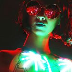 Une femme dans la nuit avec lunettes noires et des leds sur son top
