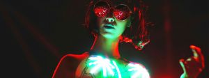 Une femme dans la nuit avec lunettes noires et des leds sur son top