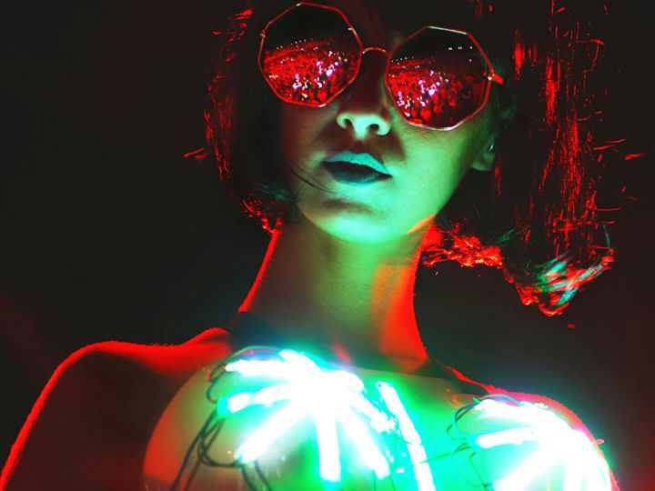 Une femme dans la nuit avec lunettes noires et des leds sur son top