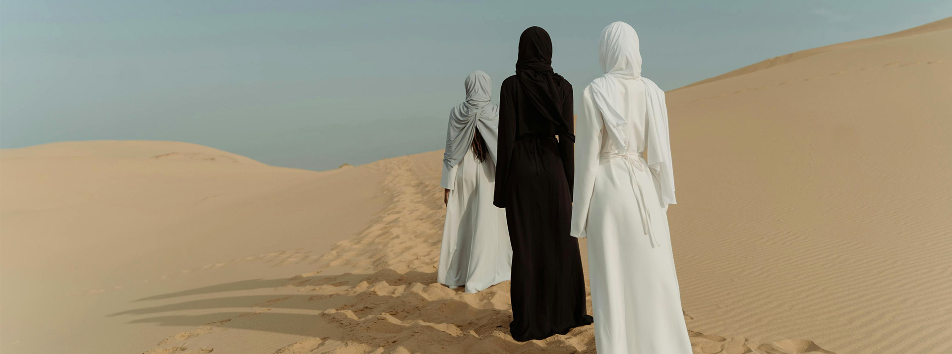 La nouvelle quête du luxe : se couper de tout, sauf de soi - L'ADN Trois femmes de dos dans le désert