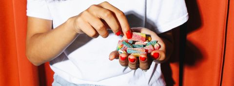 Aliments ultra-transformés : la recette du désastre Close-up sur les mains d'une jeune femme pleines de bonbons