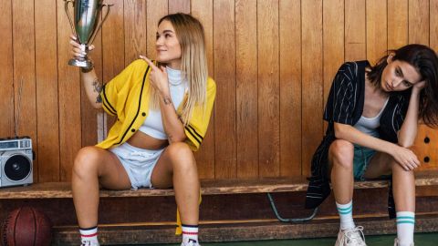 Deux filles sur un banc de sport en bois, l'une portant une coupe, l'autre dépitée