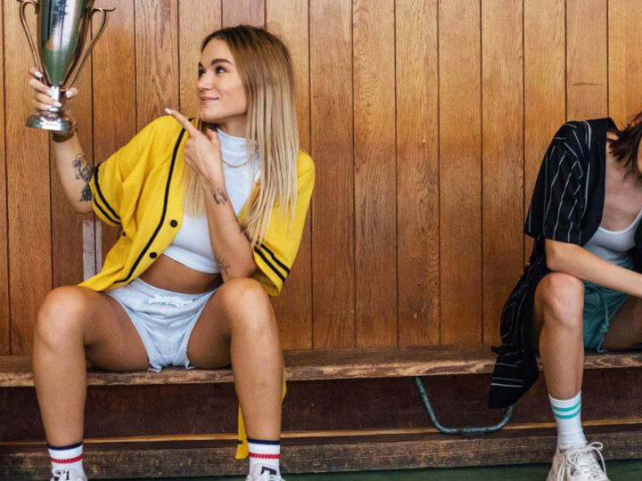 Deux filles sur un banc de sport en bois, l'une portant une coupe, l'autre dépitée