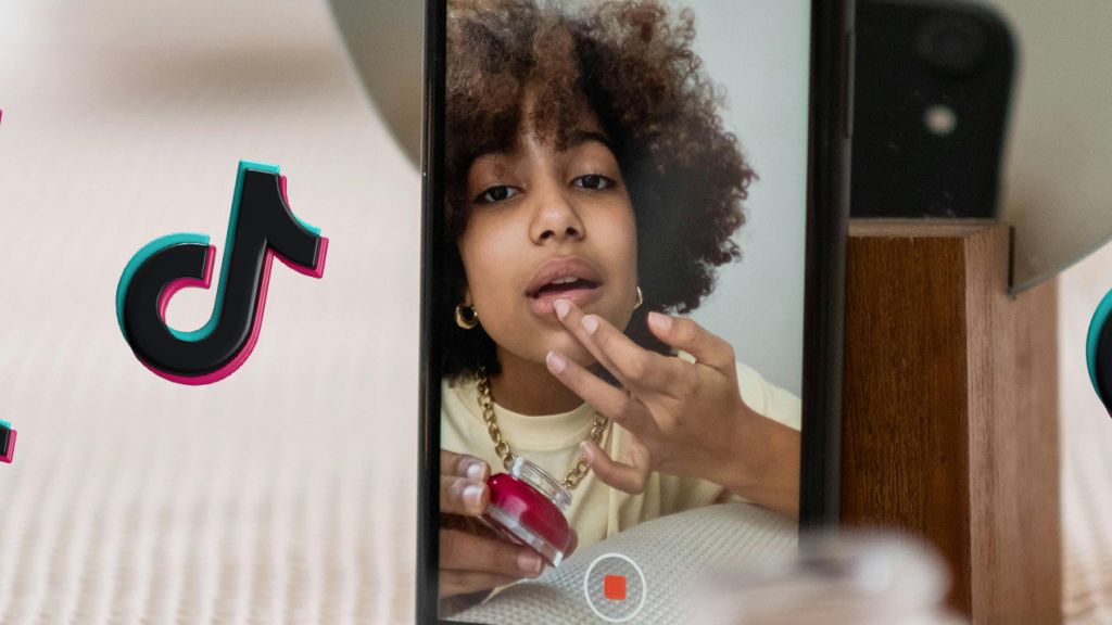 Une jeune influenceuse devant son téléphone avec des logos TikTok