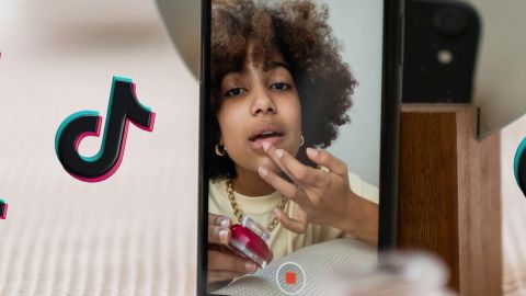 Une jeune influenceuse devant son téléphone avec des logos TikTok