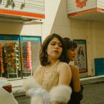 Deux filles en robes vintage dos à dos devant un cinéma à l'ancienne