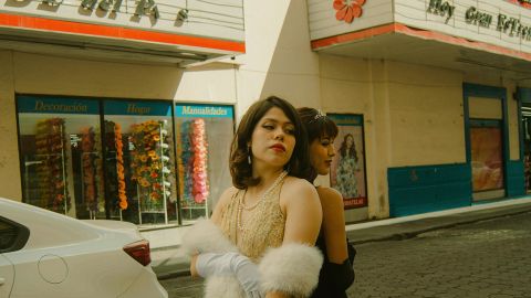 Deux filles en robes vintage dos à dos devant un cinéma à l'ancienne