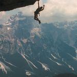 Un homme suspendu dans le vide, accroché à la montagne (image du film Cliffhanger)