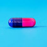 Une pilule rose et bleu sur fond bleu