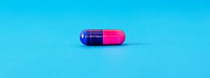 Une pilule rose et bleu sur fond bleu
