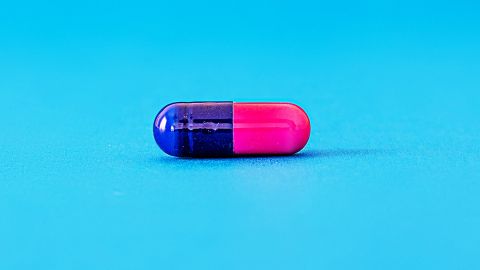 Une pilule rose et bleu sur fond bleu