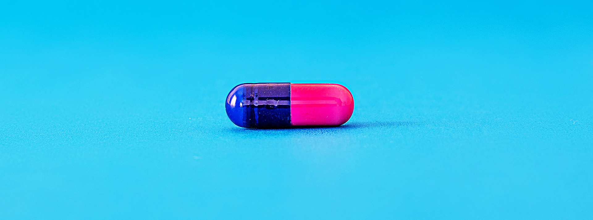 Une pilule rose et bleu sur fond bleu