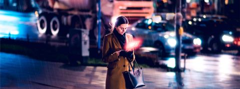 De Séoul à New York : en attendant la ville post-écran Une femme regarde son telephone dans la rue en soirée