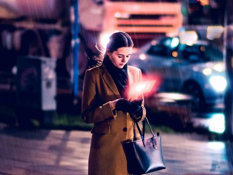 Une femme regarde son telephone dans la rue en soirée