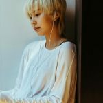 Une jeune femme asiatique avec écouteurs regarde son ordinateur portable