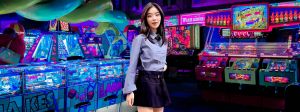 Une jeune asiatique avec une tenue d'écolière modernisée dans une salle de jeux d'arcade