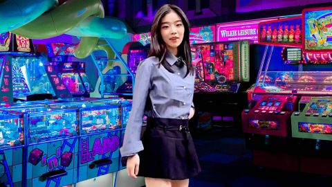 Une jeune asiatique avec une tenue d'écolière modernisée dans une salle de jeux d'arcade