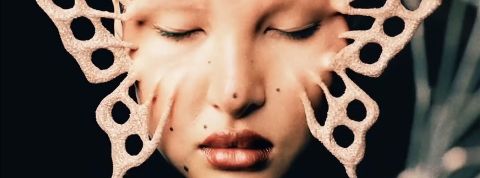 Les esthétiques de 2026 seront hybrides, bizarres et pleines de noirceur Un visage féminin dont la peau se tend et forme un papillon