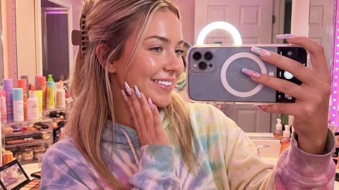 Une jeune femme influenceuse dans sa salle de bains emplie de produits de beauté