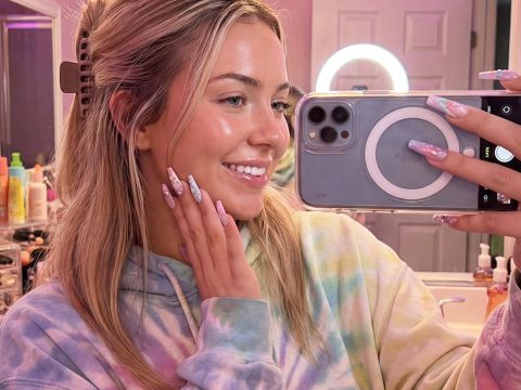 Une jeune femme influenceuse dans sa salle de bains emplie de produits de beauté