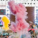 Un concert en pmein air, avec fumigènes de couleurs et une foule de spectateurs
