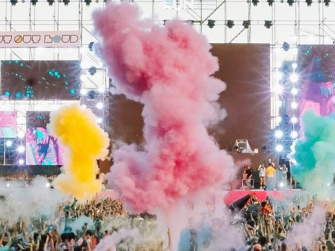 Un concert en pmein air, avec fumigènes de couleurs et une foule de spectateurs