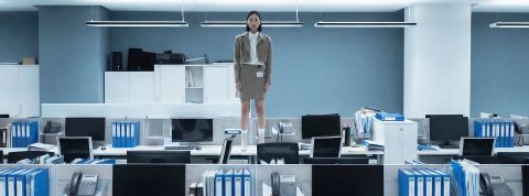 Une femme asiatique debout sur un bureau dans un open space