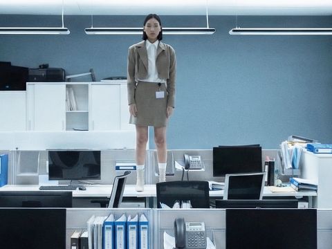 Une femme asiatique debout sur un bureau dans un open space