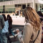 Une femme blonde de dos les yeux rivés sur son smartphone au passage piéton