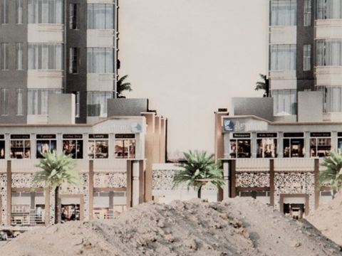 Deux immeubles modernes au Koweit derière des monceaux de sable et des palmiers