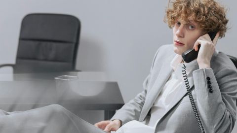 Un jeune homme les pieds sur son bureau dans un univers gris