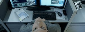 Un homme tête en arrière devant deux écrans d'ordinateurs