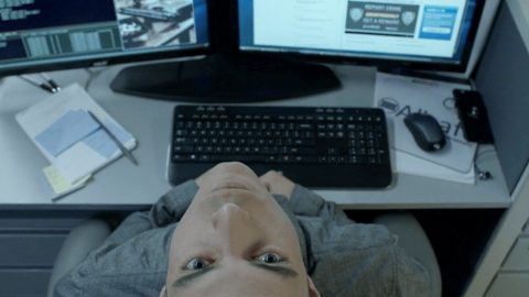 Un homme tête en arrière devant deux écrans d'ordinateurs