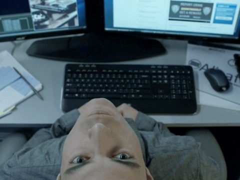 Un homme tête en arrière devant deux écrans d'ordinateurs