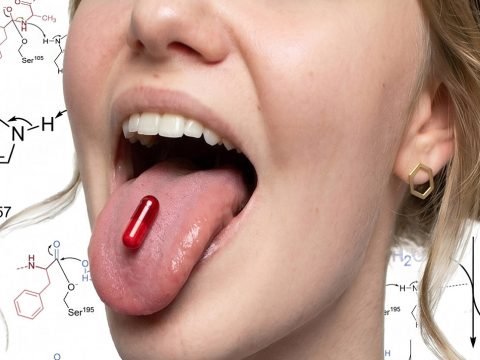 Gros plan sur une bouche de jeune femme avec une gélule rouge sur la langue