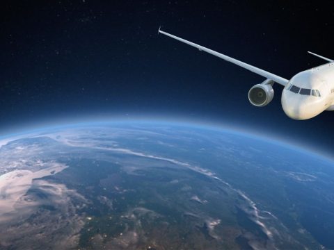 White passenger jet flying above Earth's curved horizon with a dark starry background.