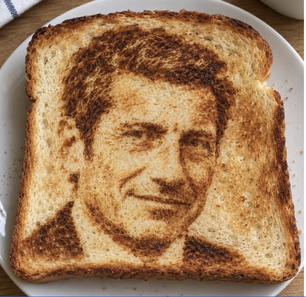 Screenshot - L'ADN Toast slice with a dark brown portrait of a man's face burned into it on a white plate
