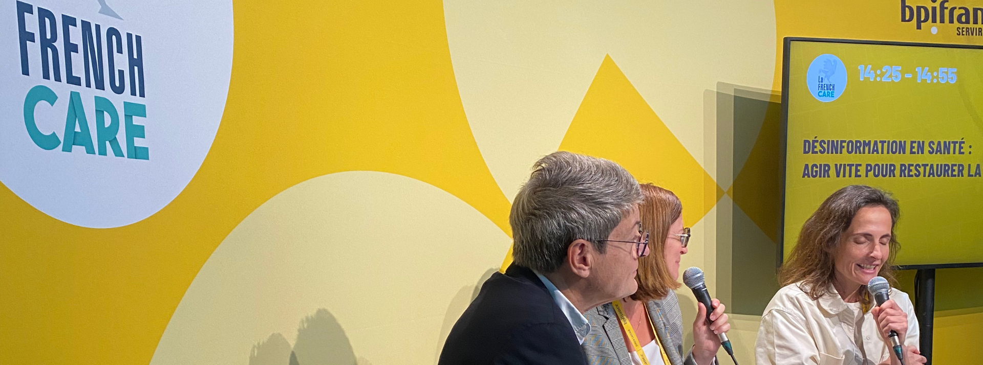 Design sans titre - L'ADN Three panelists sit with microphones on a bright yellow stage with ‘FRENCH CARE’ branding and a screen displaying session info in French.